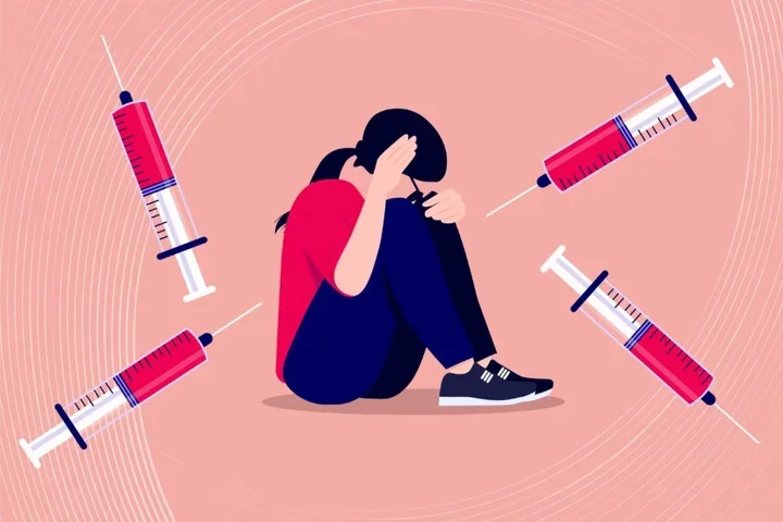 image of woman holding her heard in distress with vaccines around her