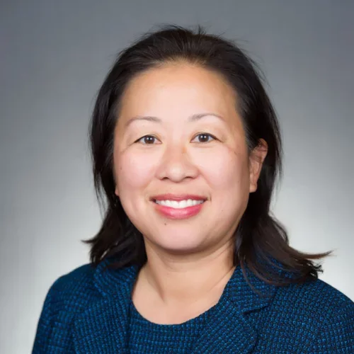Woman with black hair and blue suit smiling