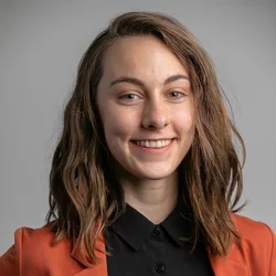 Woman smiling with black shirt and brown blazer